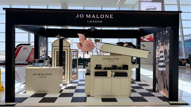 Black-framed retail brand pavilion on a chequerboard floor, installed in Bahrain airport retail